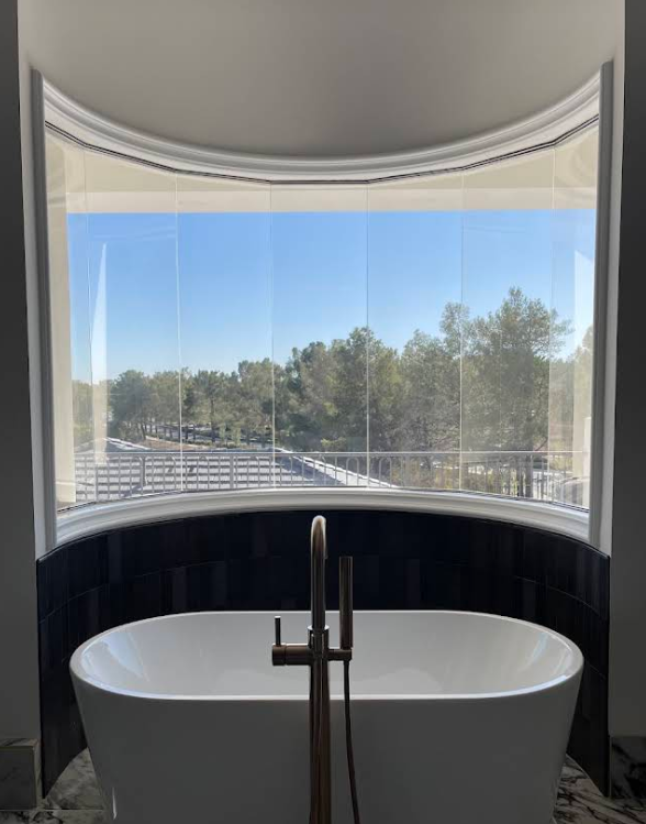 Curved residential bathroom window with clear film installed